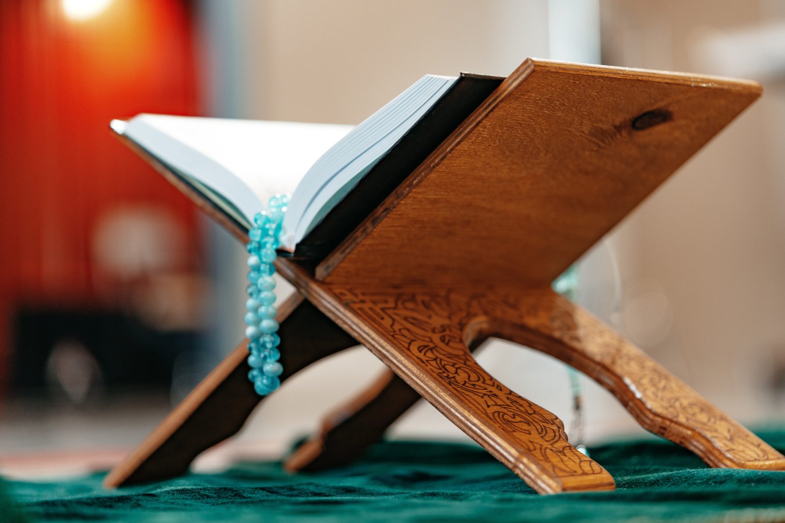 Holy Quran with prayer rosary beads on wooden stand close up